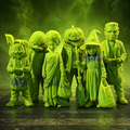 A group of small Halloween figurines or dolls dressed as monsters, ghosts, pumpkins, and a witch, posed together on a dark floor with green mist and green lighting in the background.